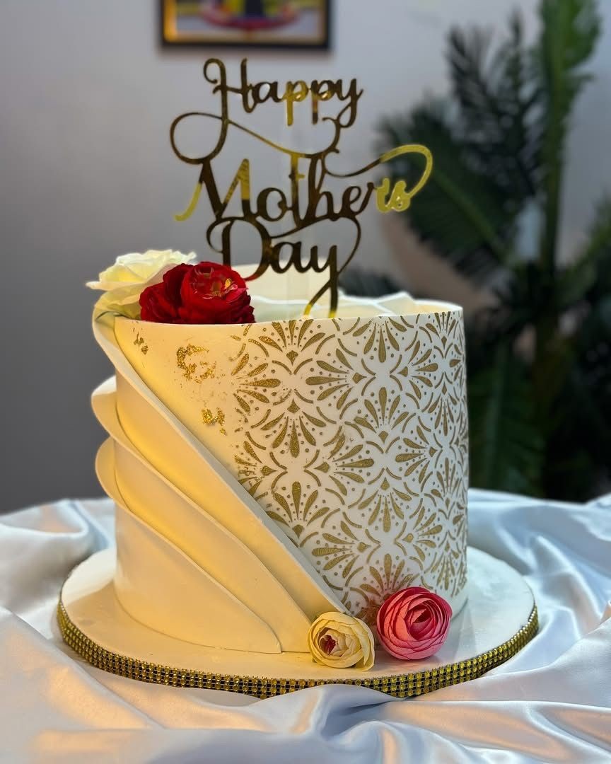 Elegant Mother's Day cake with floral design, topped with 'Happy Mother's Day' decoration and roses.
