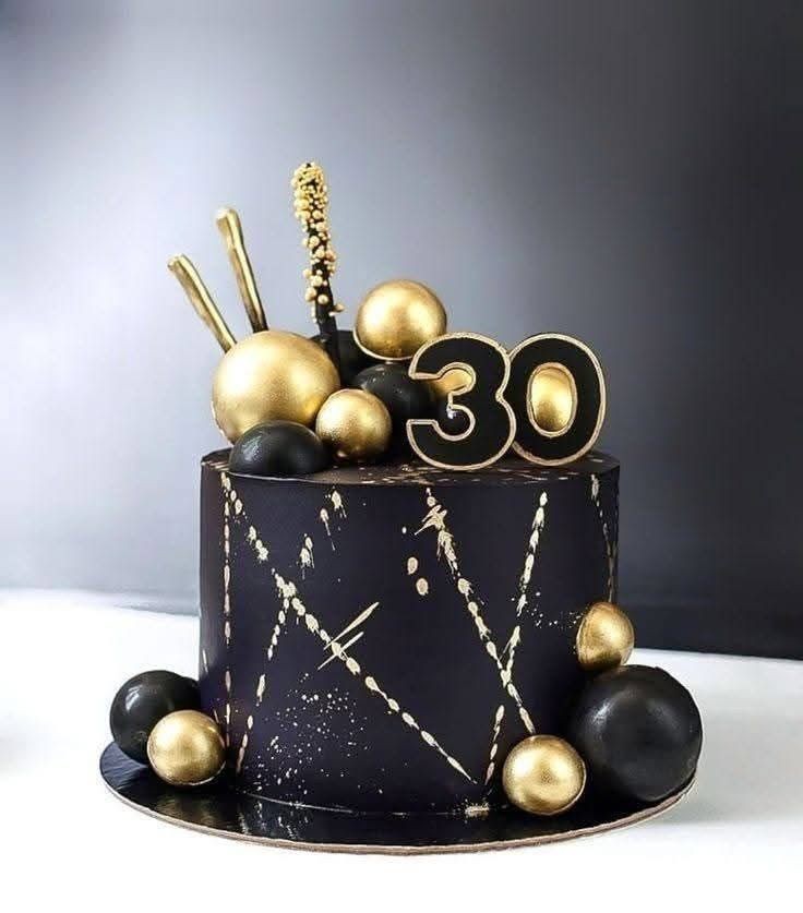 Black cake with gold accents and '30' topper, decorated with gold and black spheres.