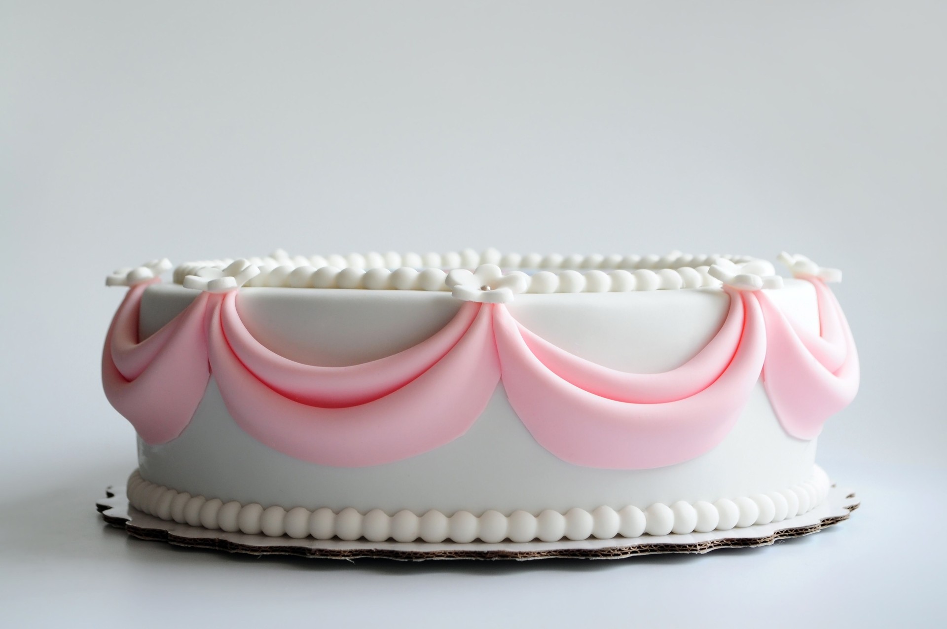 White cake with pink elements on a white background.