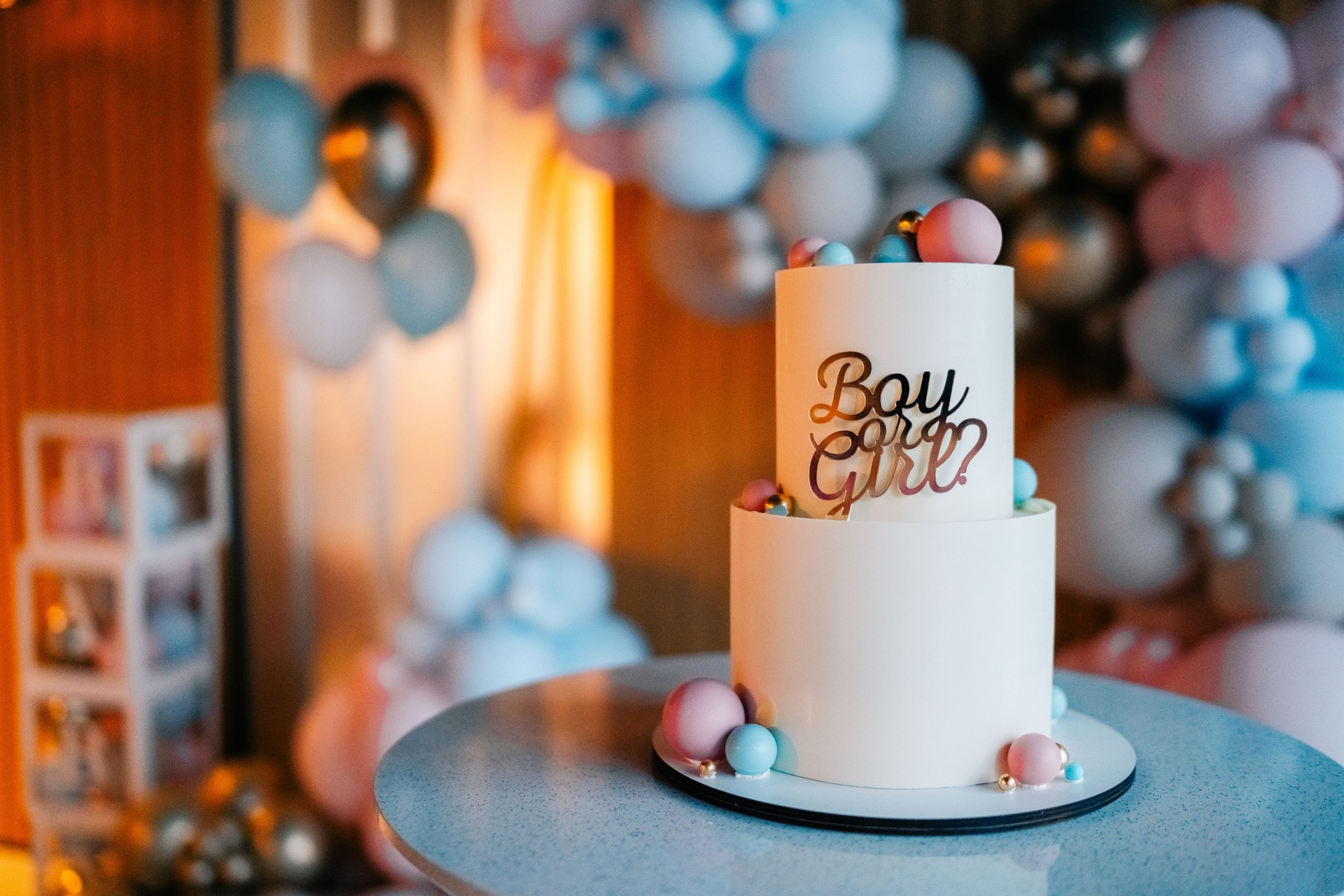 Celebration cake with boy or girl inquiry for gender reveal party, decorated with pastel colors and balloons
