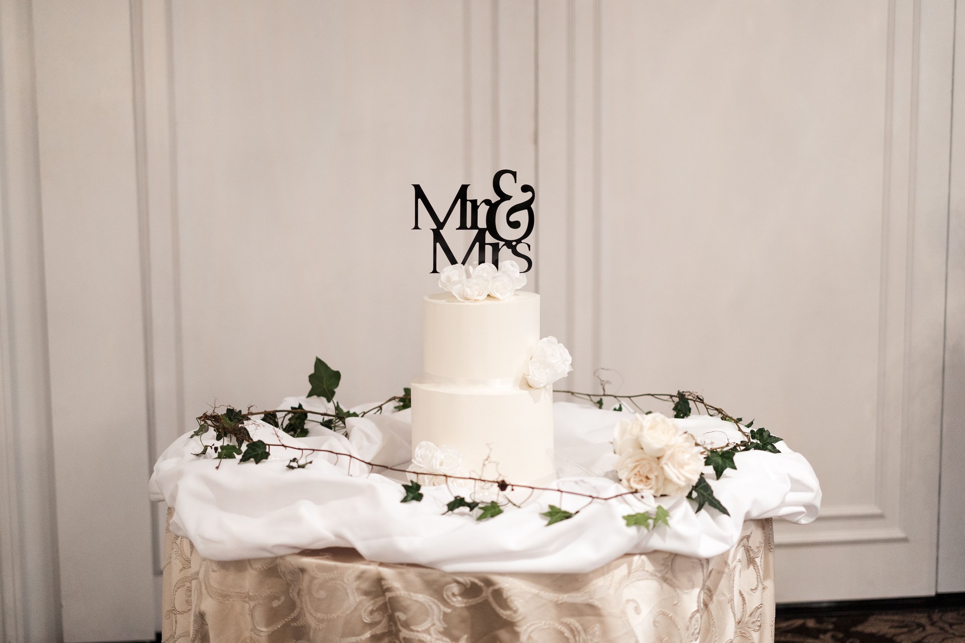 Beautiful two-tier wedding cake with Mr & Mrs topper decorated with flowers